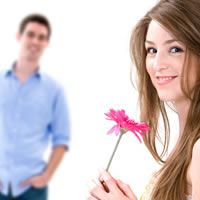 Girl holds flower in front of guy